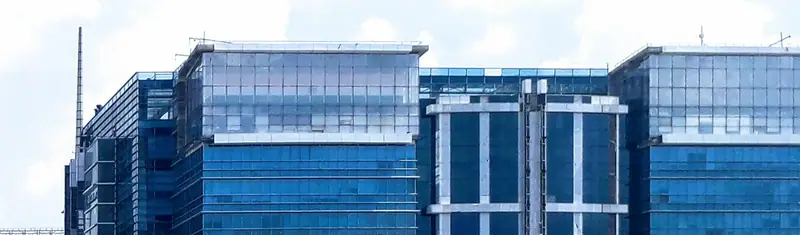 Glass office towers against a bright sky in Gurugram