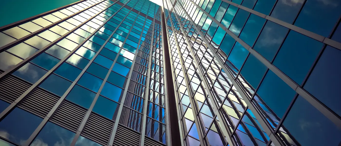 Glass facade reflecting a clouded sky