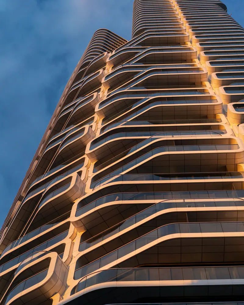 Curved, warmly lit balconies on a residential tower at blue hour